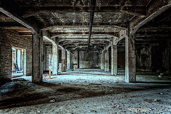 Abandoned industrial basement with concrete pillars and debris