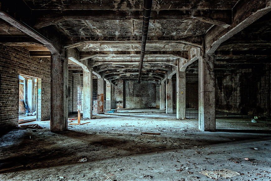 Abandoned industrial basement with concrete pillars and debris