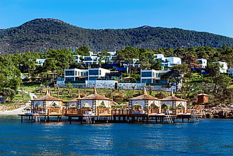 Luxury overwater cabanas with modern villas on hillside