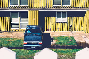 Blue SUV parked in front of yellow apartment building
