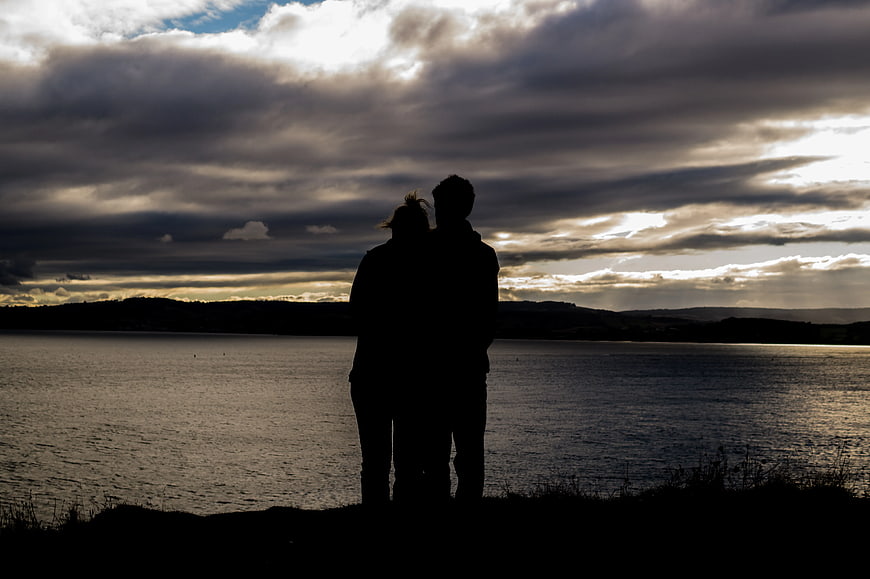 Silhouette of Couple Standing by Lake at Sunset