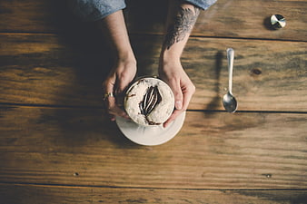 Top view of hands holding frothy cappuccino on wooden table