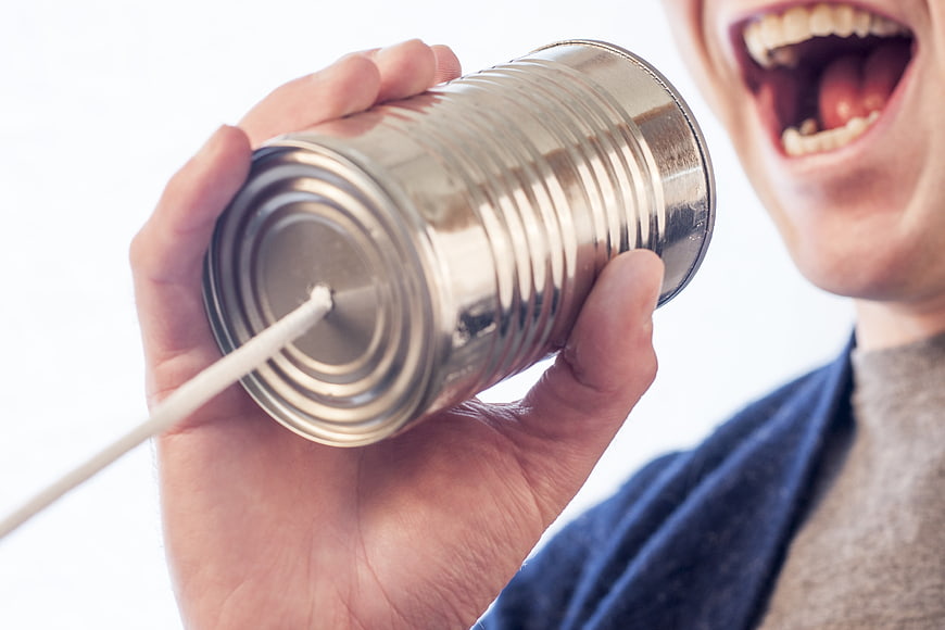 Man Shouting Into Tin Can Telephone Against White Background