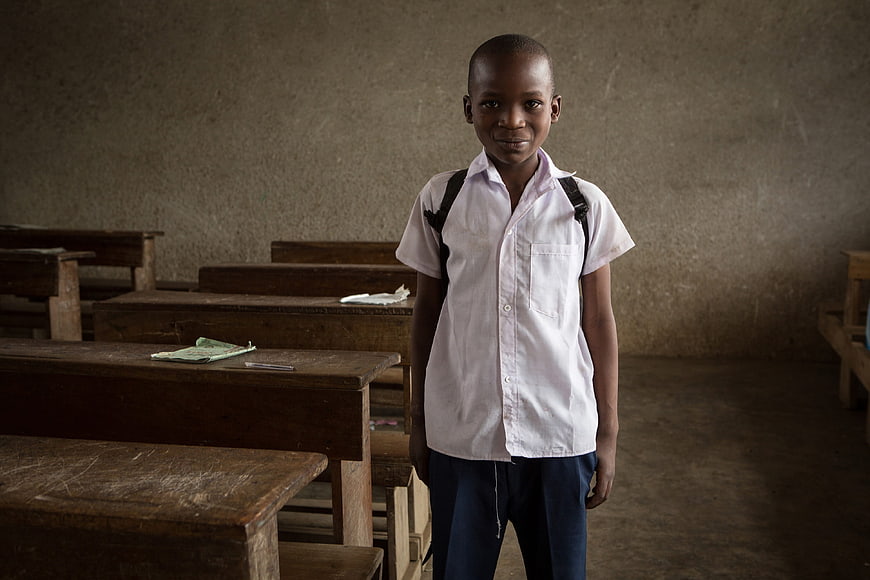 Young African schoolboy standing in a rustic classroom