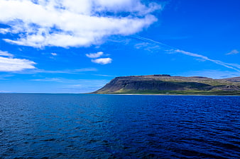 Vibrant Blue Ocean and Mountain Landscape with Clouds