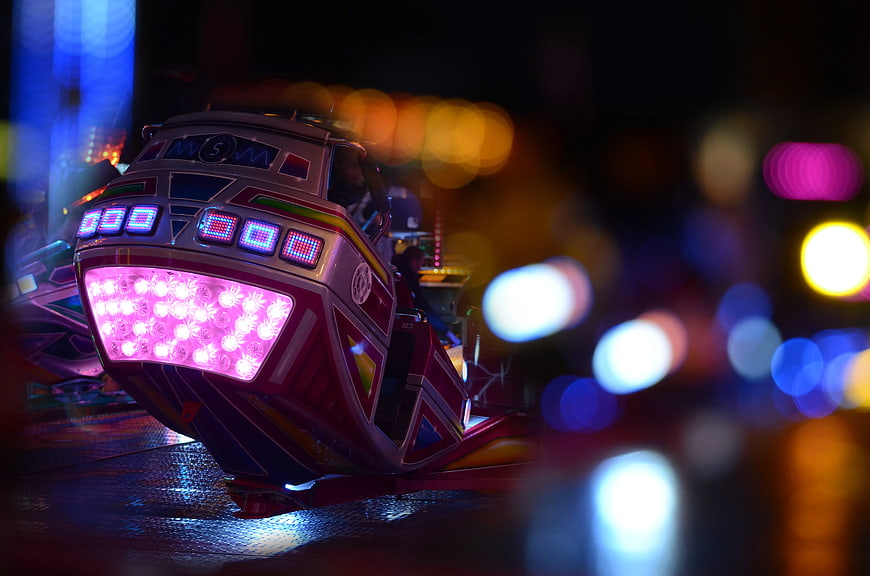 Neon-lit bumper car at night with colorful bokeh background