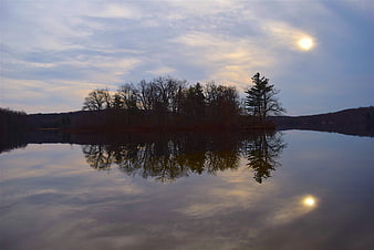 Serene Lake Reflection with Sun and Bare Trees