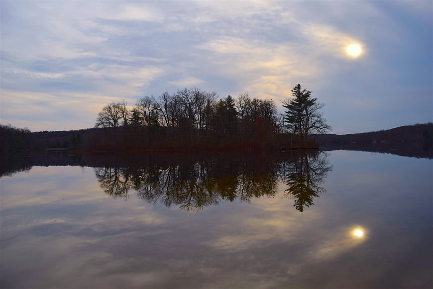 Serene Lake Reflection with Sun and Bare Trees