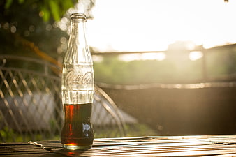 Glass Coca-Cola Bottle on Bamboo Table at Sunset