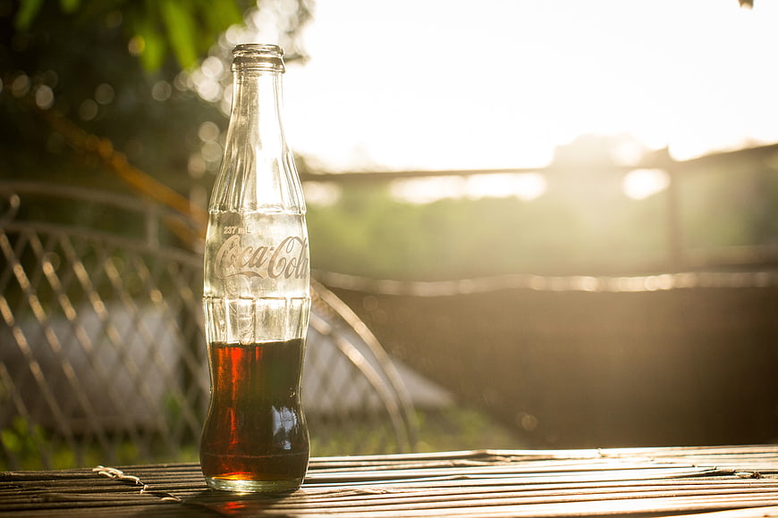 Glass Coca-Cola Bottle on Bamboo Table at Sunset
