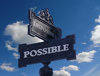 Street sign pointing to possible and impossible against blue sky