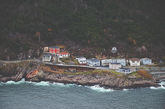 Coastal village on rocky cliffside with ocean waves