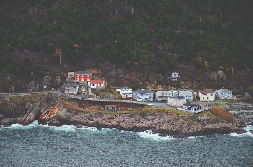 Coastal village on rocky cliffside with ocean waves