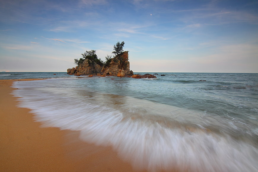 Long Exposure Rocky Beach with Silky Waves and Blue Sky