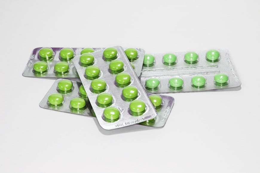 Green pills in blister packs on white background