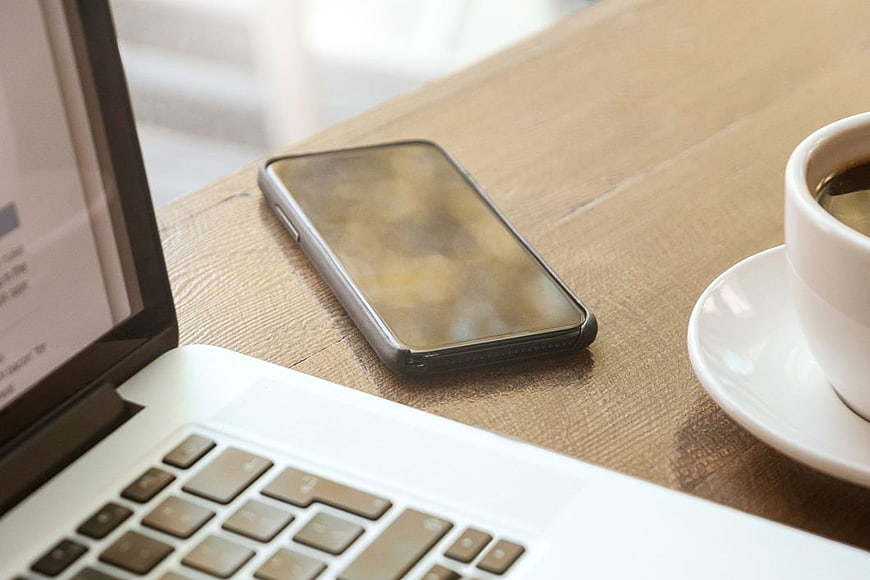 Laptop, Smartphone, and Coffee on Wooden Desk