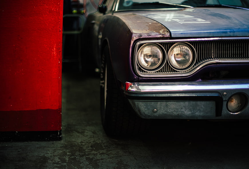Close-up of vintage muscle car front with red wall