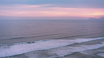 Serene Ocean Sunset with Pink Sky and Rolling Waves