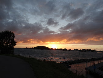 Dramatic sunset over lake with clouds and dock