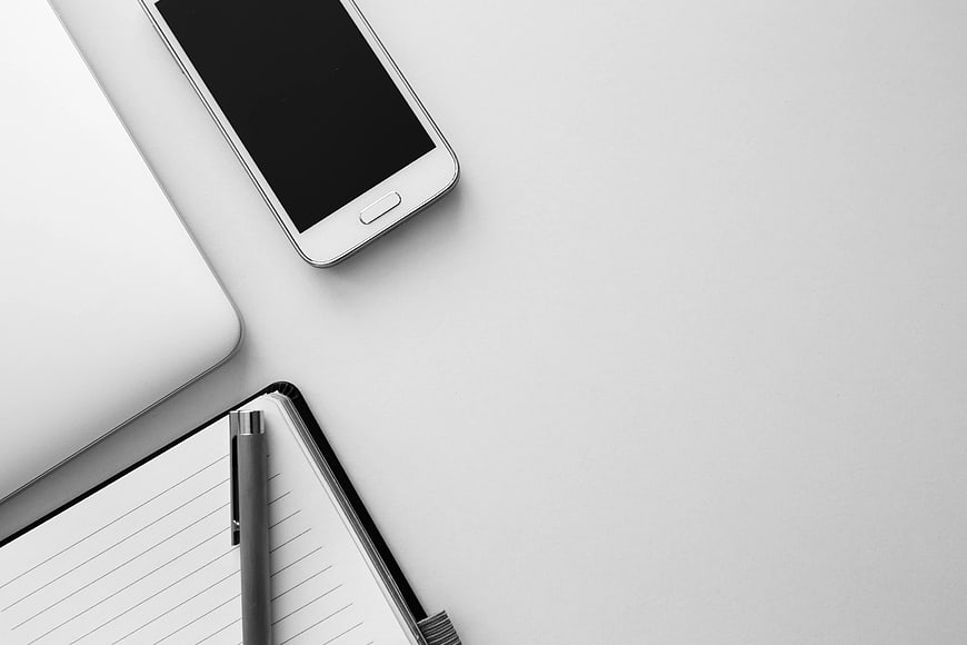 Minimalist workspace with smartphone, laptop, and notebook