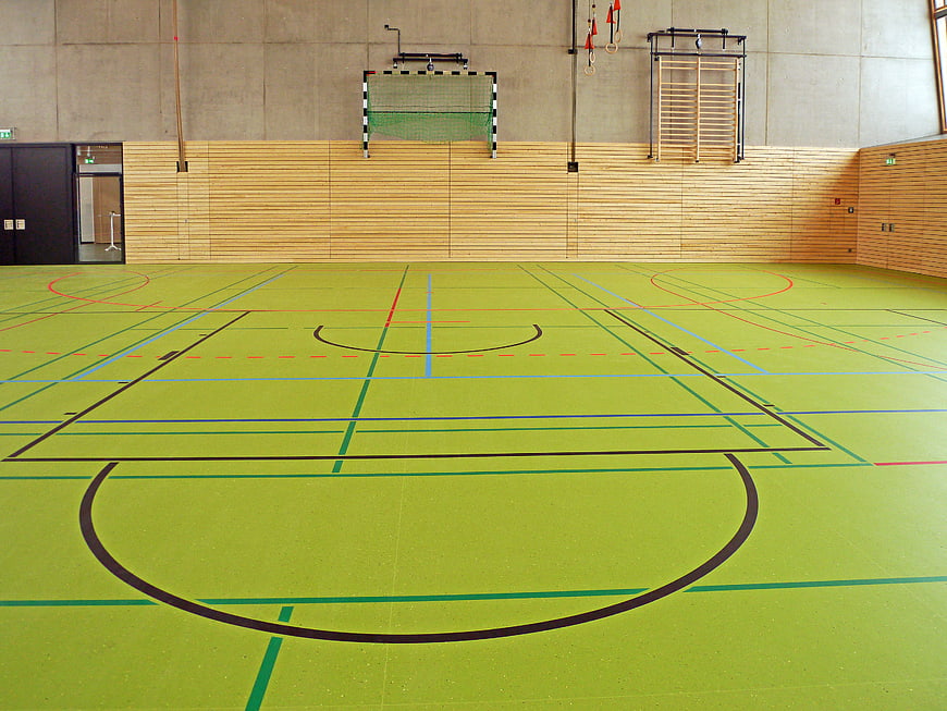 Empty indoor sports hall with green multi-purpose floor