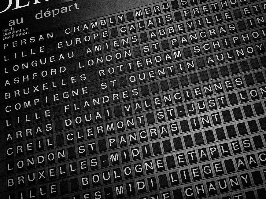 Black and white train station departure board with city names