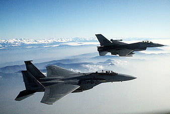 Two Military Fighter Jets Flying In Formation Over Snowy Mountains