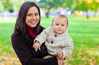 Happy Mother Holding Baby in Autumn Park