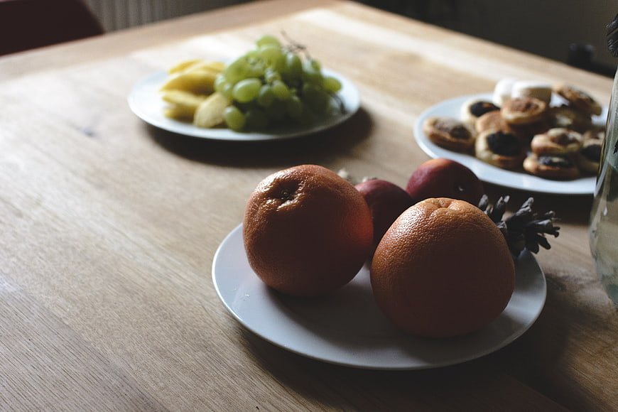 Fresh oranges and fruit platters on a wooden table