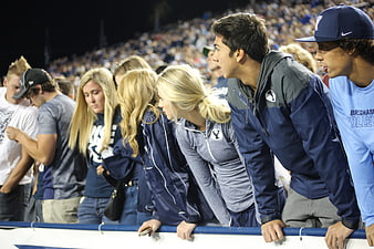 Young Spectators Watching Sports Game In Stadium Crowd