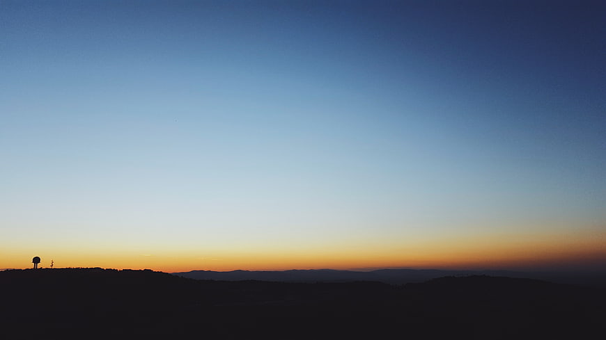 Silhouette of rolling hills against a twilight sky gradient