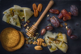 Gourmet Cheese Platter with Honey, Nuts, and Dates on Slate