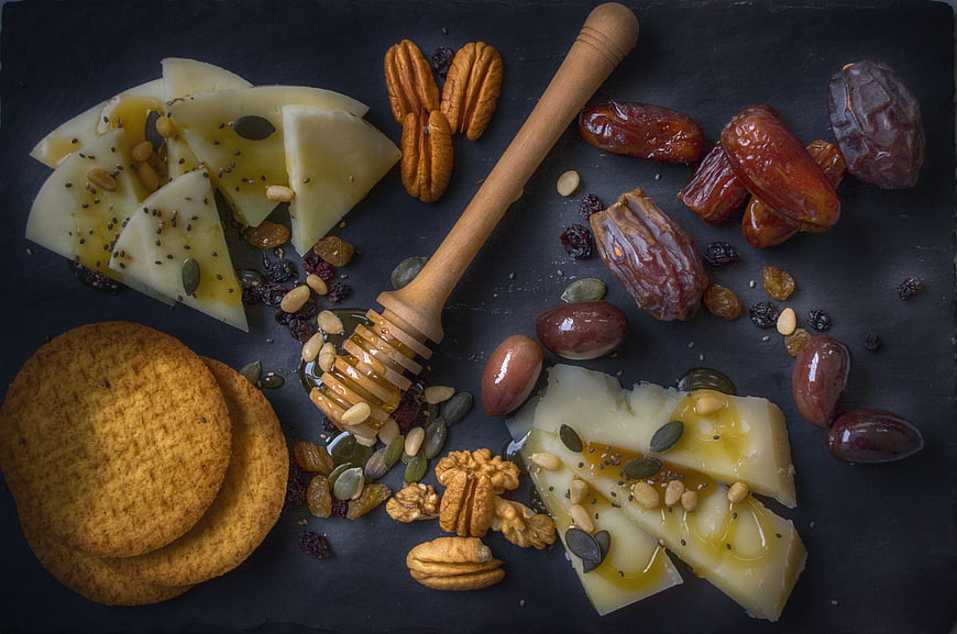 Gourmet Cheese Platter with Honey, Nuts, and Dates on Slate