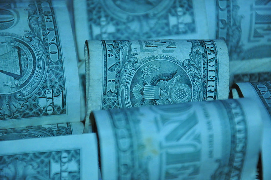 Close-up of rolled US one dollar bills with cool blue tint