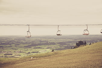 Empty ski lift chairs overlooking green mountain valley landscape