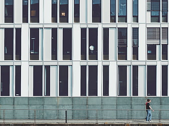 Man walking past modern white office building facade