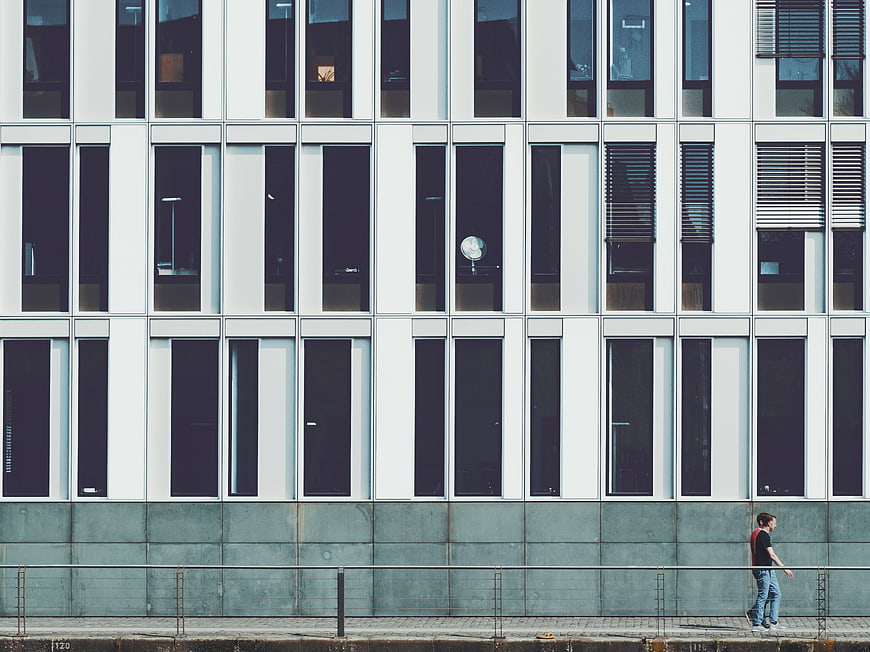 Man walking past modern white office building facade