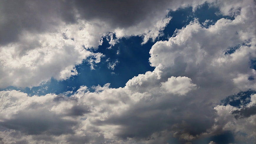 Dramatic blue sky with dark storm clouds and bright white gaps