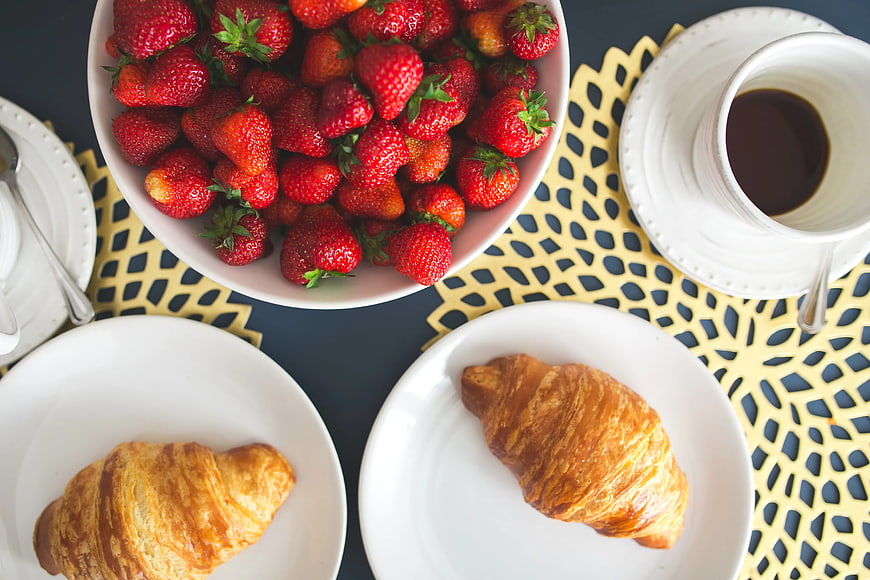 Top view of croissants, strawberries, and coffee on a table