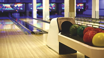 Colorful Bowling Balls on Return Rack in Empty Alley
