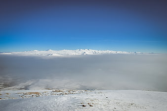 Snowy mountain peaks above sea of clouds winter landscape