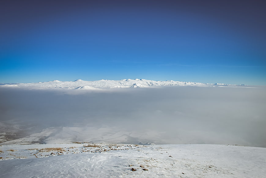Snowy mountain peaks above sea of clouds winter landscape