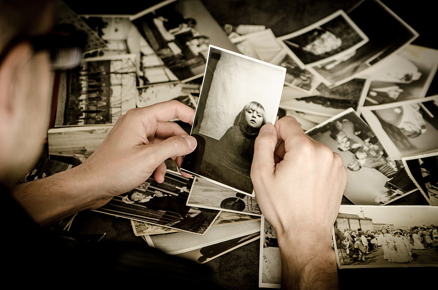 Hands holding vintage black and white photograph over scattered memories