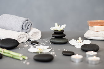 Spa wellness setup with stones, towels, and orchids