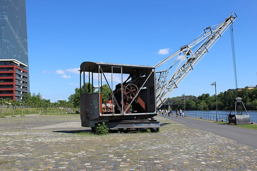 Old Rusty Crane on Cobblestones Near Modern Skyscraper