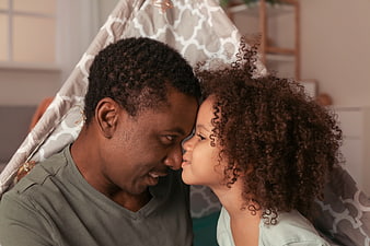 Father and daughter touching foreheads in a cozy indoor tent