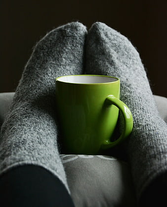 Green mug resting on cozy gray wool socks