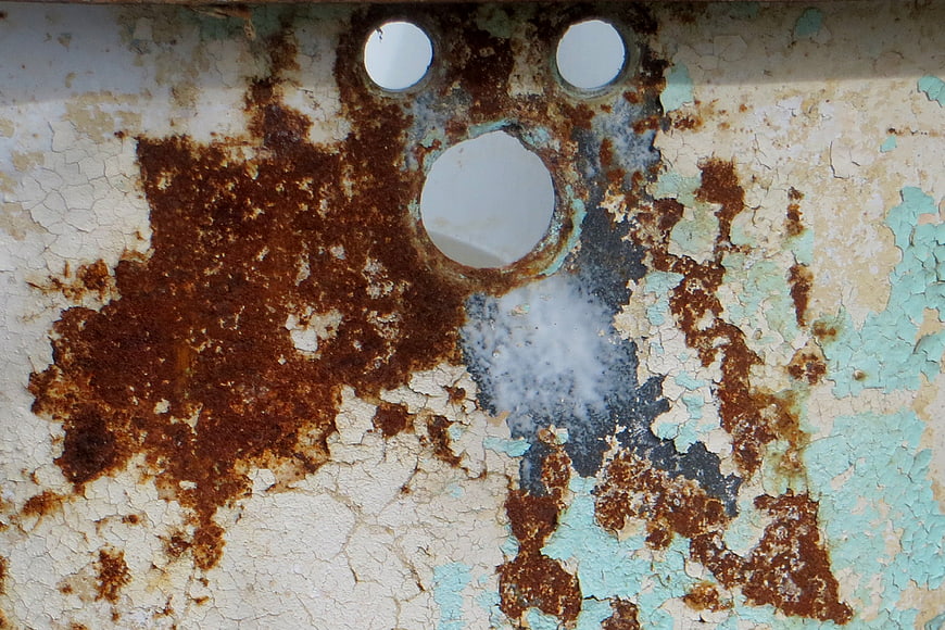 Rusty metal surface with peeling paint and holes