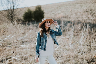 Woman in denim jacket and hat in dry field