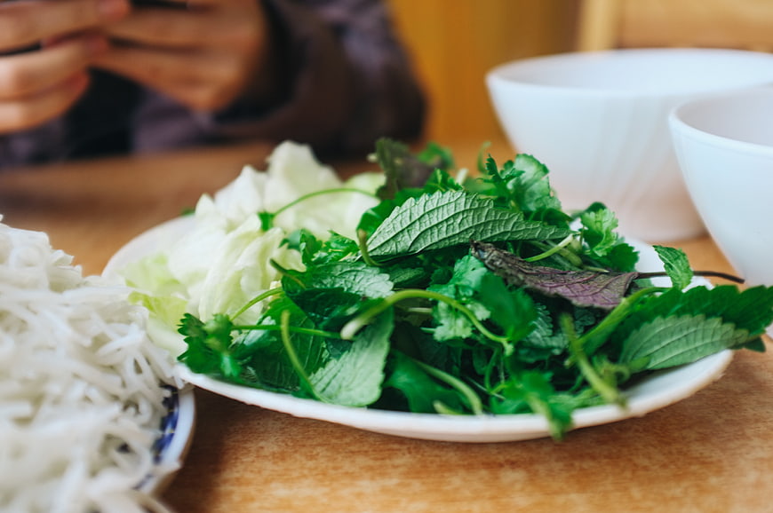 Fresh Vietnamese herbs and rice noodles on wooden table